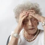 Older woman with her hands on her forehead in a stressed out manner