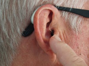 Man points at his hearing aid.