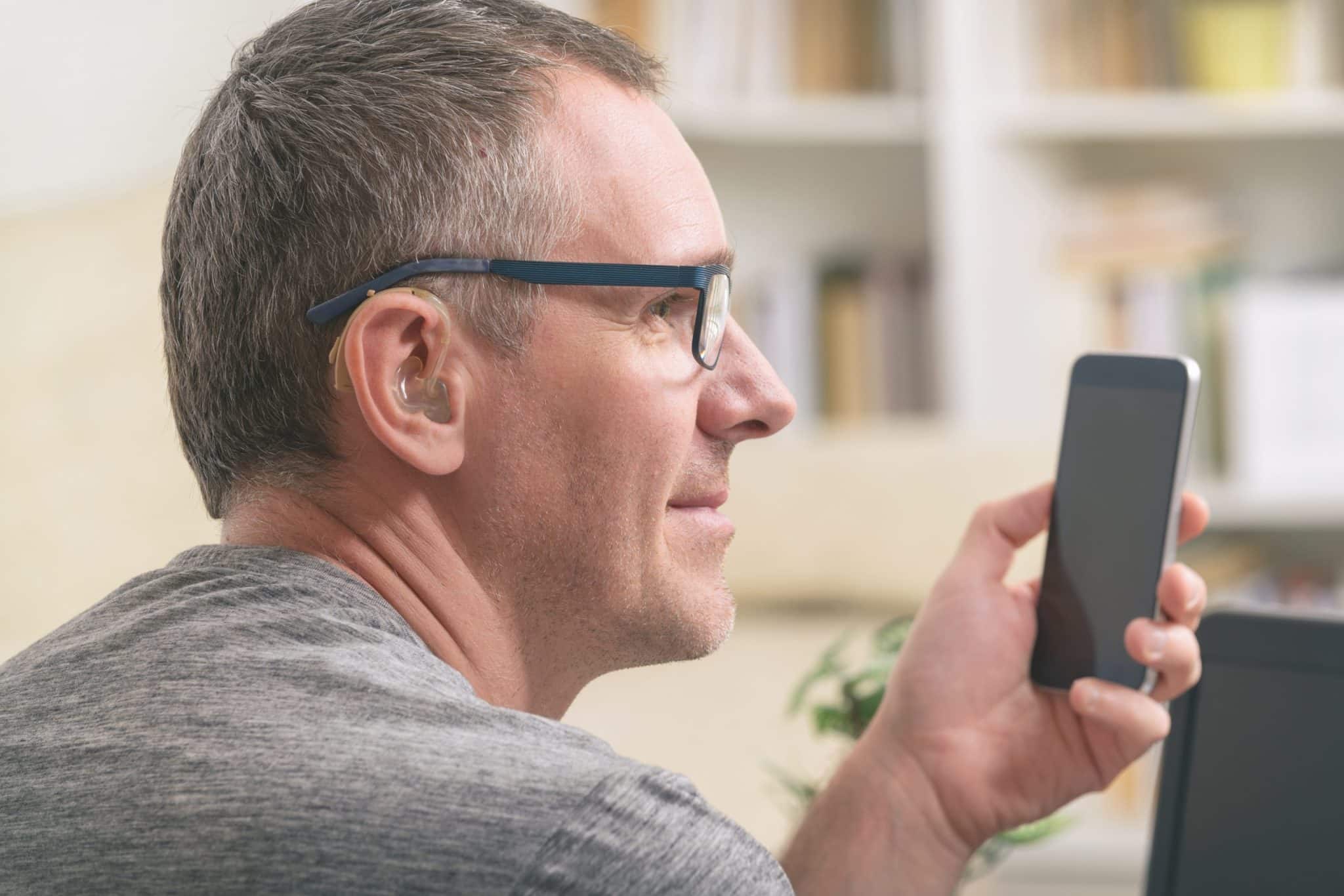 Man with hearing aids uses a smartphone.