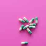 A pile of common pills on a pink background.
