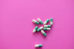 A pile of common pills on a pink background.