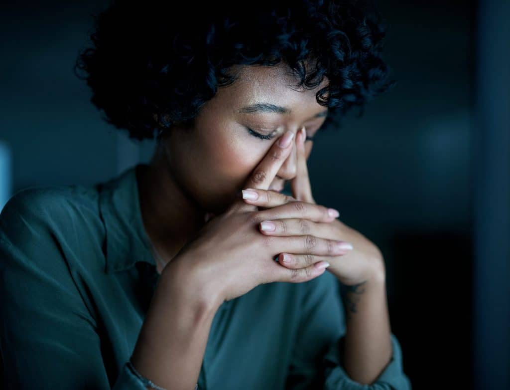 A stressed out woman holding her hands to her face.