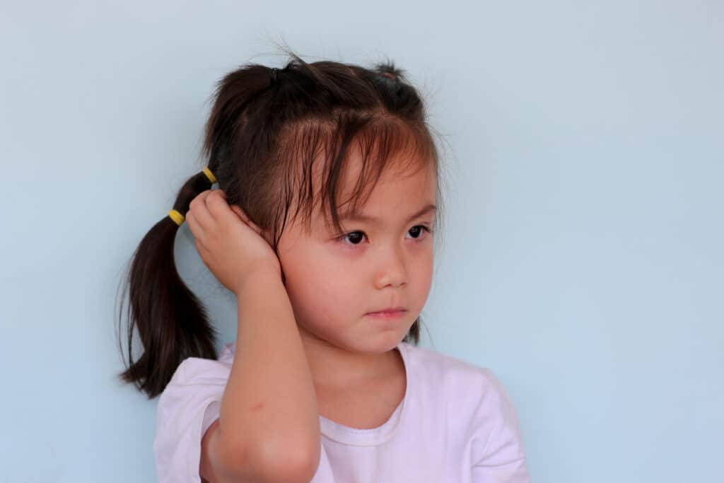 Young girl covers ear with hand 