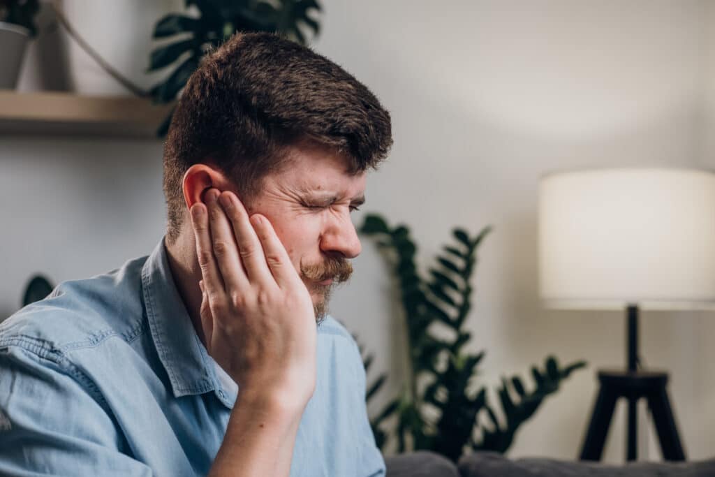 Man with tinnitus holding his ear