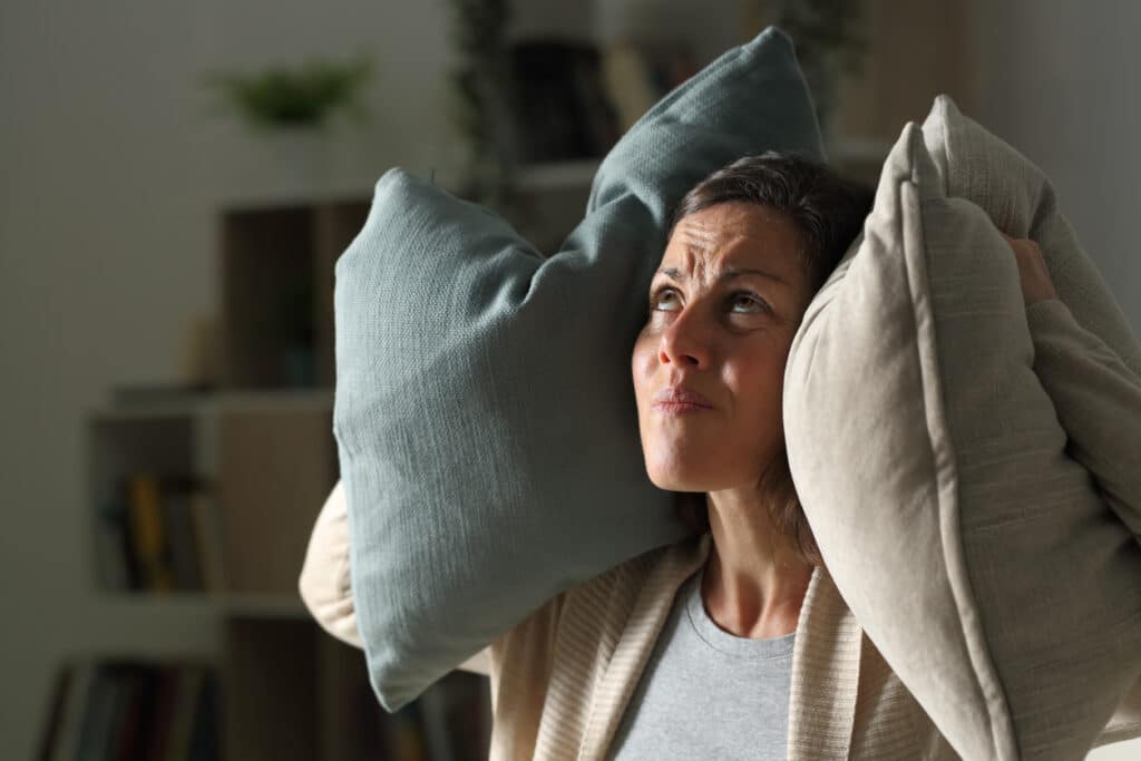 Woman covering her ears with pillows.