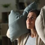Woman covering her ears with pillows