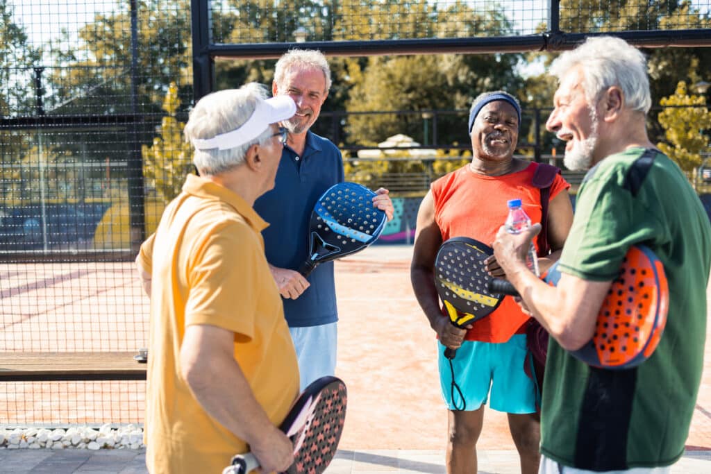 Four seniors hanging out on the pickleball court.