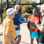 Four senior men hanging out on the pickleball court