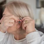 Woman Holding A Hearing Aid Up to her Ear