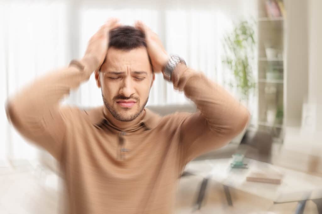 Man with tinnitus holding his head, blurred effect.